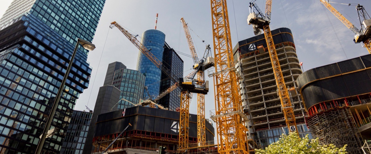 Innerstädtische Großbaustelle mit mehreren Turmdrehkranen zwischen Hochhäusern